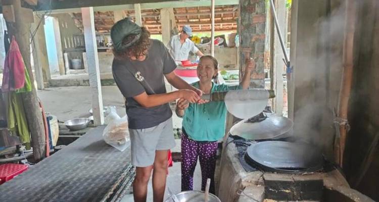 Deux personnes pratiquant une activité traditionnelle avec des outils locaux dans un espace ouvert.