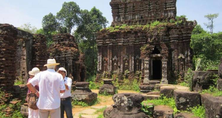 Des touristes explorant des ruines antiques par une journée ensoleillée.