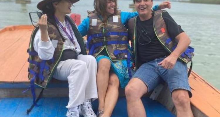 Trois personnes dans un bateau portant des gilets de sauvetage, profitant d'une excursion sur l'eau.