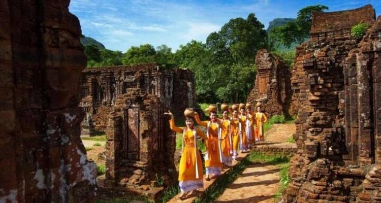 Groupe de personnes en tenue traditionnelle marchant à travers des ruines antiques.