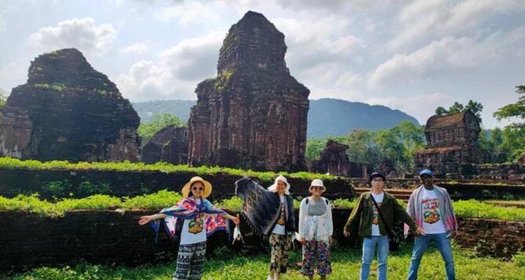 Des personnes posant devant des ruines antiques avec un arrière-plan montagneux pittoresque.