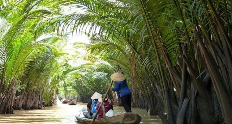 Touristen rudern in Booten auf einem Wasserweg mit dichtem Blattwerk