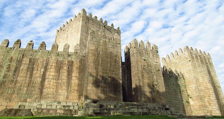 Mittelalterliche Steinmauern mit Türmchen unter einem blauen Himmel.