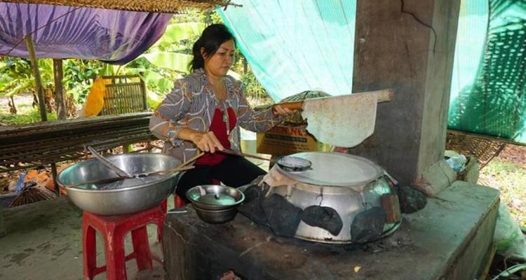 Vrouw kookt traditioneel eten in een rustieke keuken.