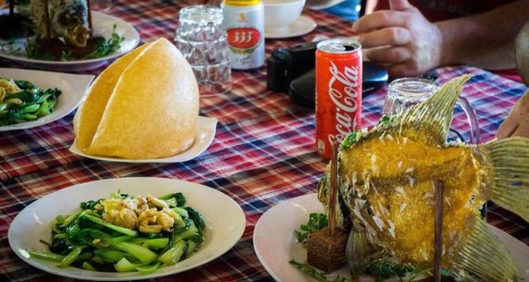 Vietnamese maaltijd op een geruit tafelkleed met vis en groenten.