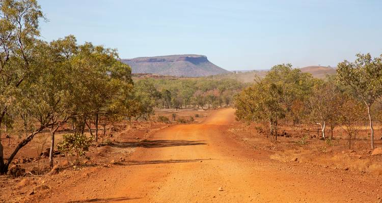 Stoffige outback weg die leidt naar verre, platte heuvels.