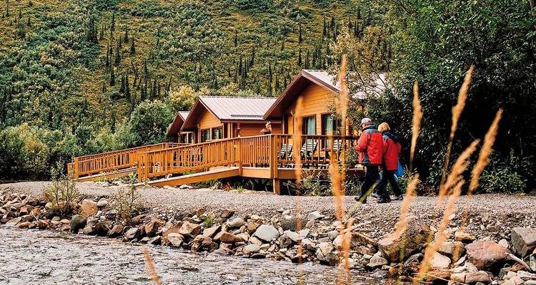 Paar, das entlang eines felsigen Bachs bei einer Hütte spaziert.