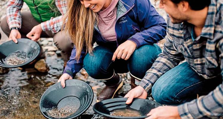 Menschen, die in einem seichten Bach nach Gold schürfen.