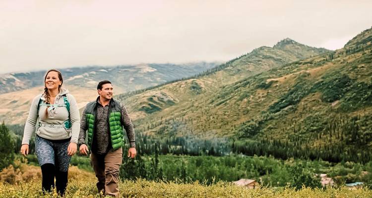 Paar wandert in hügeliger Landschaft.
