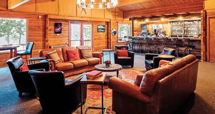 Gemütliches Interieur einer Lodge mit Ledersitzgelegenheiten und einer Bar.