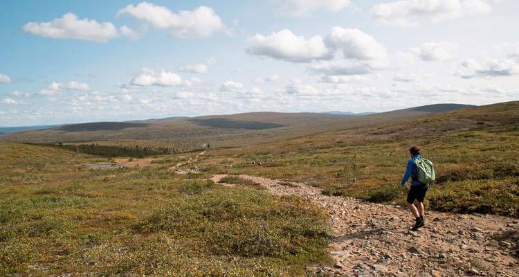 A person hiking along a trail with vast open landscapes.