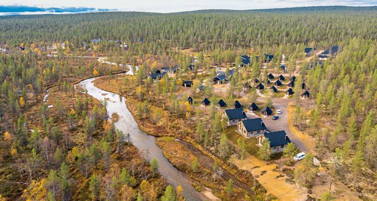 Aerial view of a resort area with multiple cabins and a river winding through.