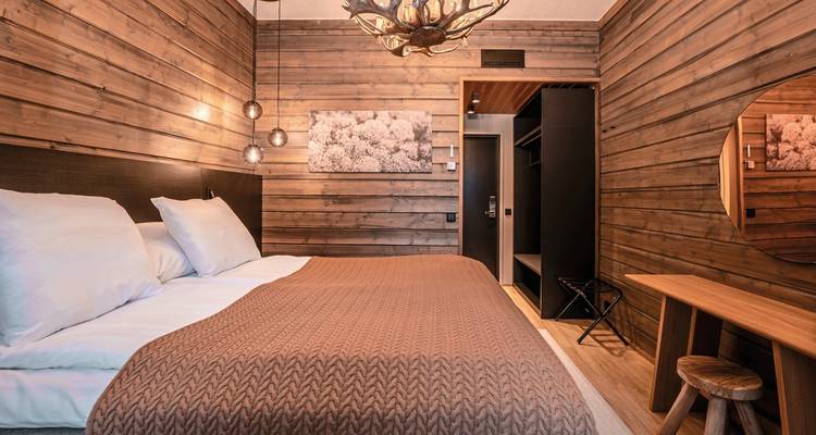Rustic bedroom with wooden walls and cozy bedding.