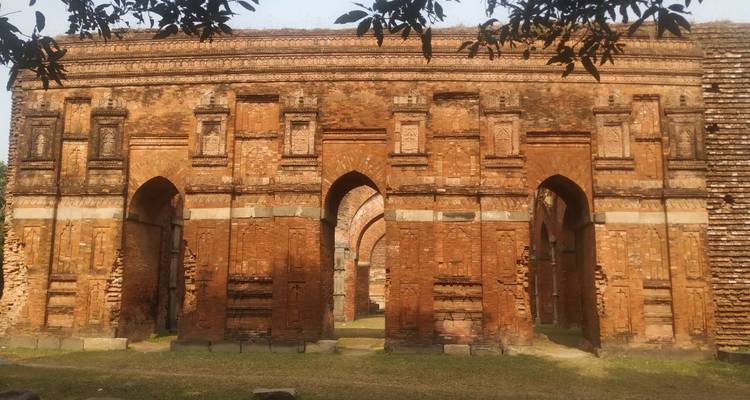 Weathered red-brick arches of a historic temple complex bask in soft afternoon light.