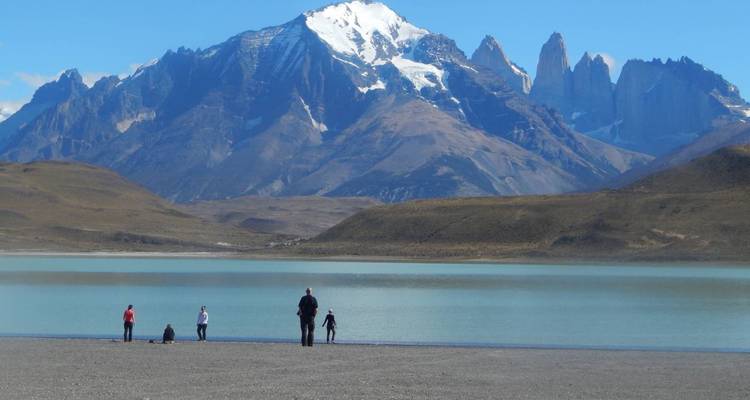 Familie und Kinder erkunden den Kieselstrand eines türkisfarbenen Sees unter den Granittürmen von Torres del Paine