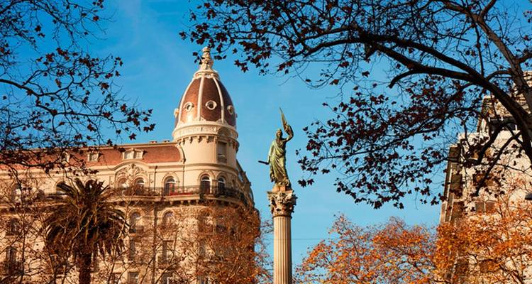 Herbstlicher Stadtplatz mit Statue und historischen Gebäuden.
