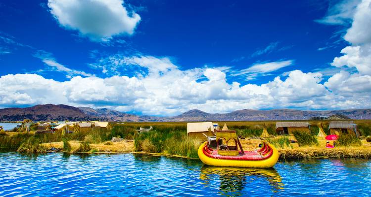 Huttes flottantes en roseau et un bateau jaune vif sur un lac.
