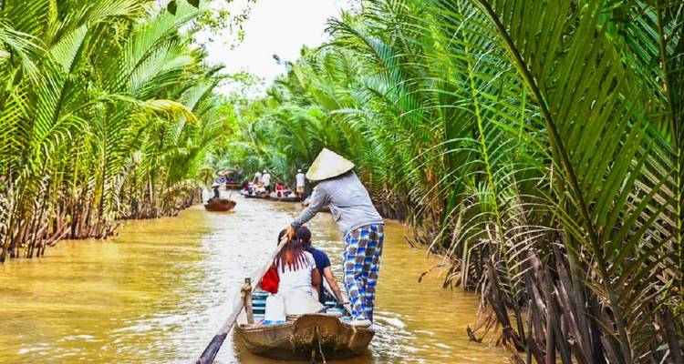 Person paddling a boat through a lush, narrow waterway.