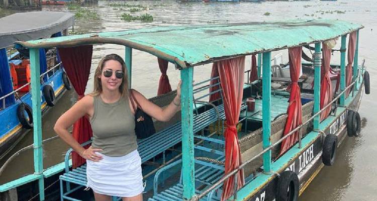 Woman standing next to a traditional wooden boat.