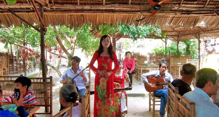 Group people enjoying live traditional music under a thatched roof.