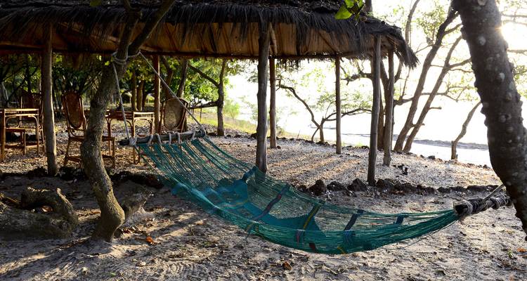 Hamac sous un toit de chaume à côté de la plage.