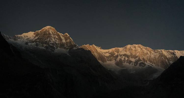 Berge, die im Morgengrauen beleuchtet sind.
Or more concisely:
Von der Morgendämmerung beleuchtete Berge.