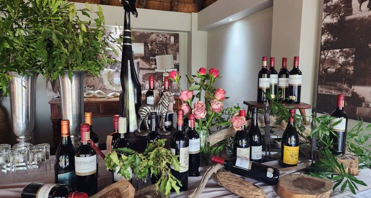 Diverse wijnflessen tentoongesteld in een kamer met planten.