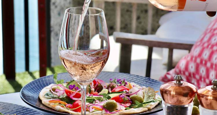 Rosé wijn die in een glas wordt geschonken op een eettafel.