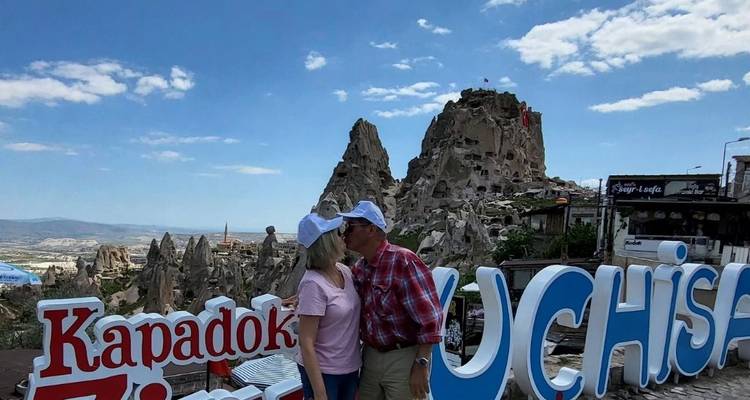 Pareja compartiendo un beso frente a un telón de fondo rocoso y el cartel de 'Uchisar'.