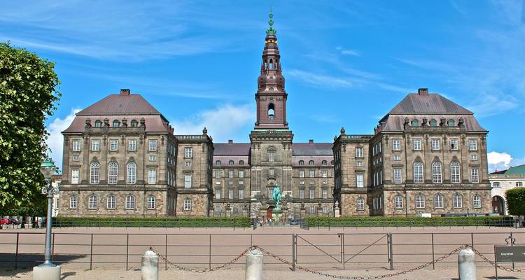 Voorkant van Copenhagens imposante Christiansborg Palace onder een heldere blauwe hemel.