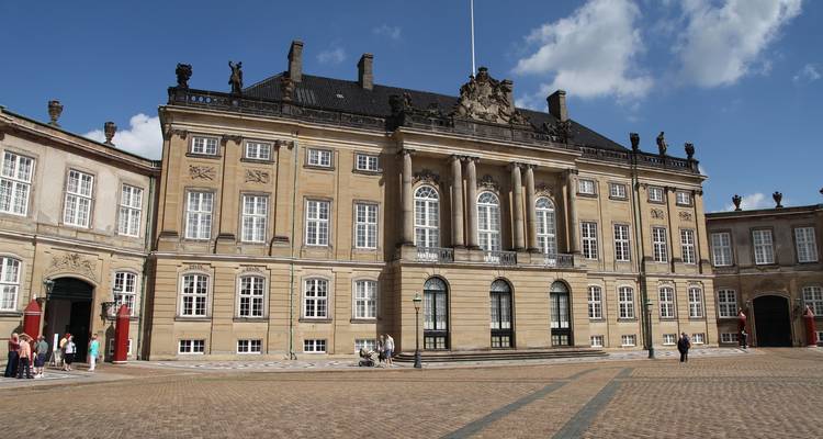 Bezoekers verzamelen zich in de ruime binnenplaats van Amalienborg Palace met zijn neoklassieke gevel.