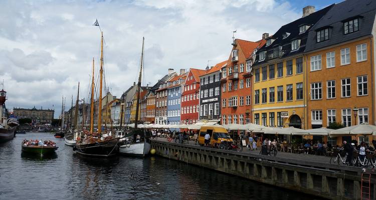 Drukke Nyhavn-haven met kleurrijke gebouwen uit de 17e eeuw, hoge masten en openlucht cafés.