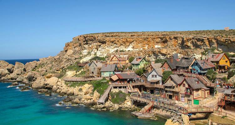 Pueblo acantilado de casitas de madera coloridas con vistas al agua turquesa brillante en Popeye Village, Malta.