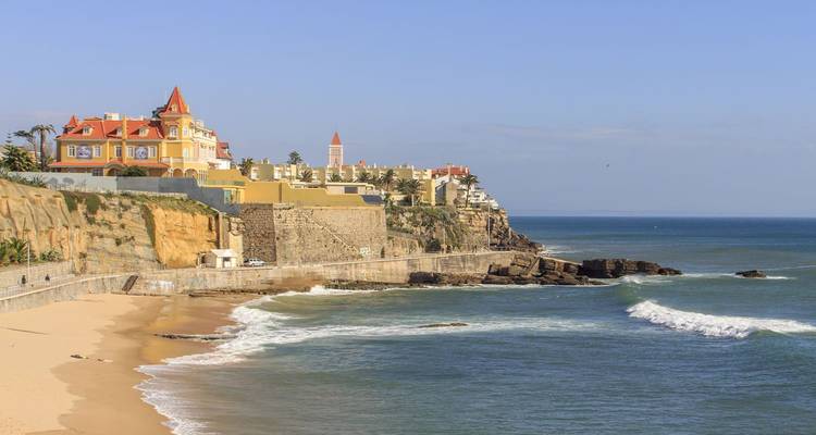 Elegant seaside villas on a rocky bluff overlooking waves along the Estoril coast
