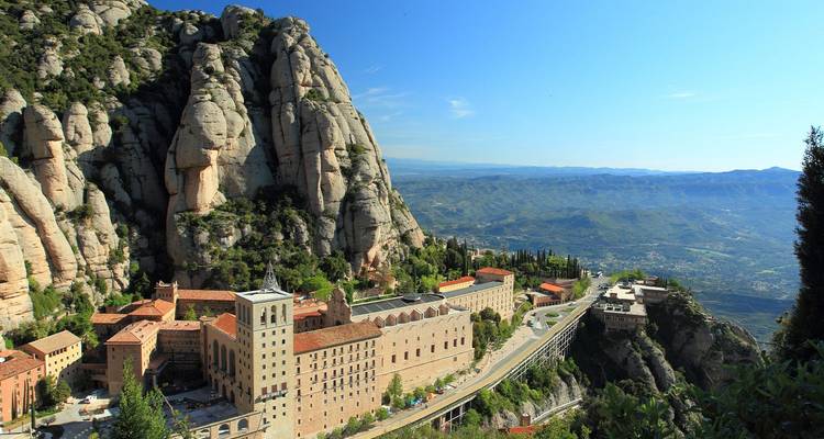 El monasterio de Montserrat acurrucado bajo los dramáticos picos dentados de las montañas que dominan un amplio valle