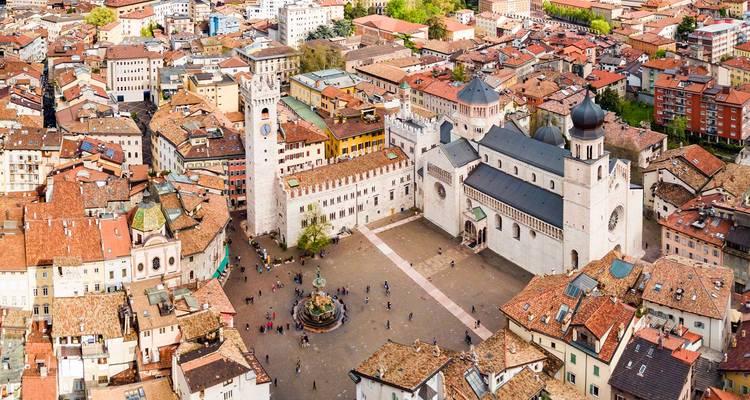 Panorama aérien de la Piazza Duomo de Trente présentant la cathédrale, le clocher et la fontaine entourés de toits en terre cuite.