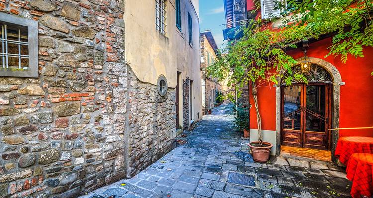 Charmante smalle kasseienstraat in Lucca omzoomd met stenen en kleurrijke gevelgebouwen.