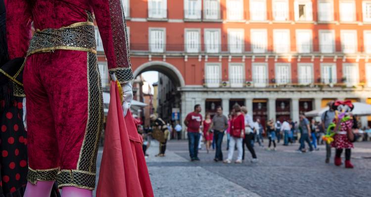 Artista disfrazado mirando hacia los ajetreos de las calles empedradas de Plaza Mayor en Madrid.