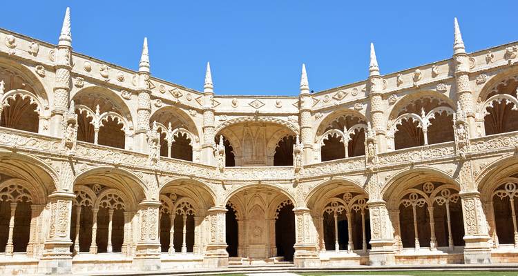 Claustro de dos niveles intricadamente tallado de un monasterio histórico bajo un cielo azul despejado