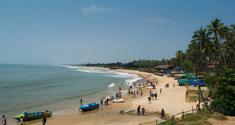 A sandy beach with people enjoying water activities.