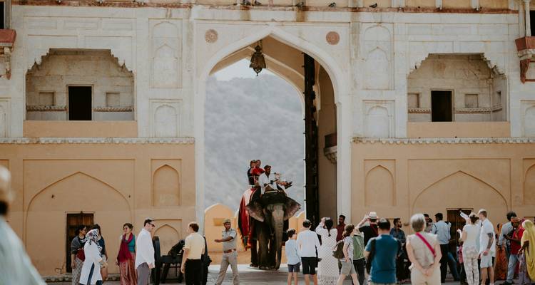 People entering a historic fort on an elephant.
Dutch translation: Mensen die een historisch fort binnentreden op een olifant.