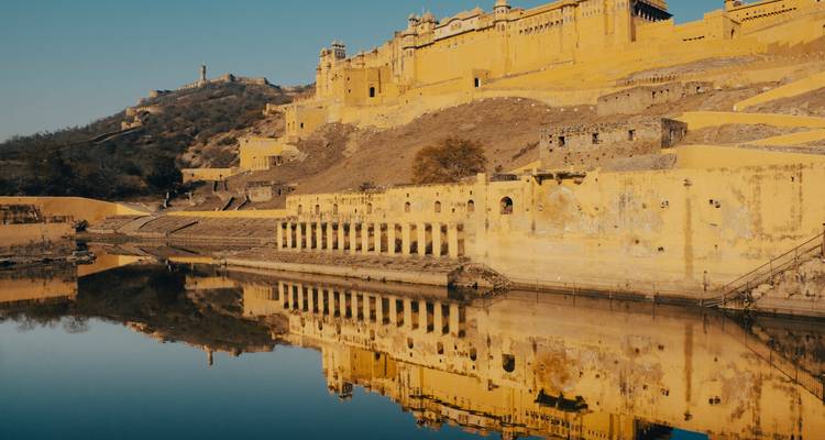 A majestic fort with yellow walls reflecting in a calm lake.
