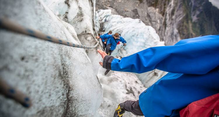 Primer plano de escaladores agarrándose de la cuerda fija mientras suben por la pared de glaciar helado.