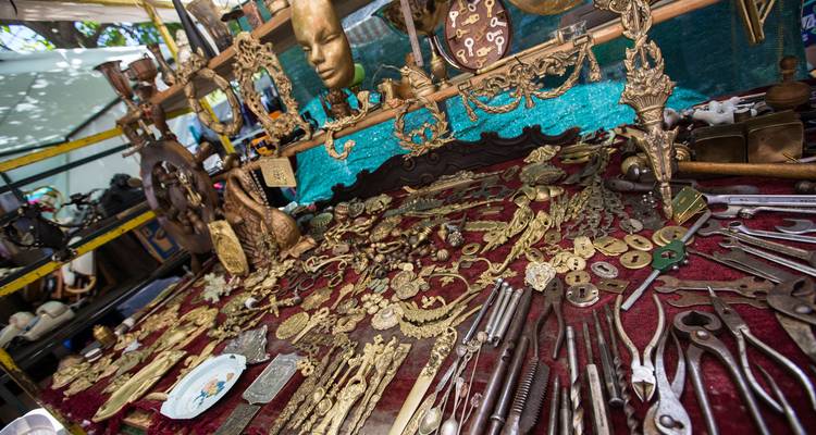 Vista amplia de artículos antiguos variados en un puesto de mercadillo cubierto con tela.