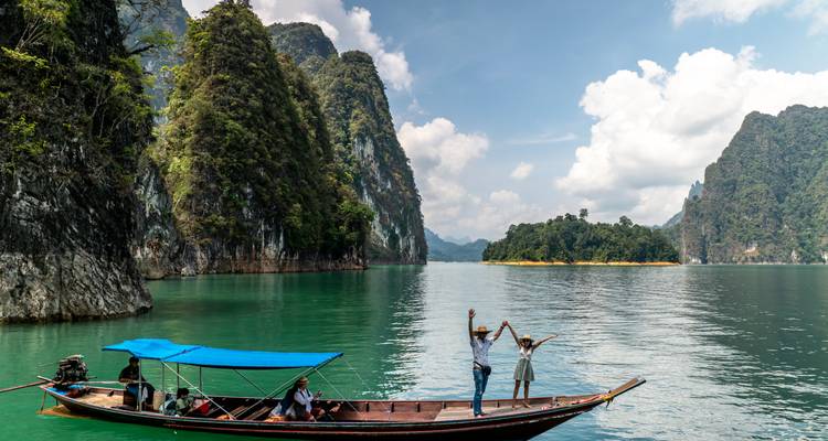 Mensen op een longtailboot in een serene meer met omringende kliffen.