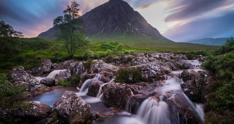 Bergszene mit einem Wasserfall und Grün in der Abenddämmerung.
