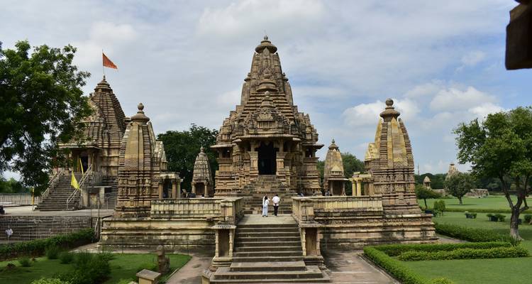 Eine Frontansicht eines verzierten, antiken Tempels mit Grün rundherum.