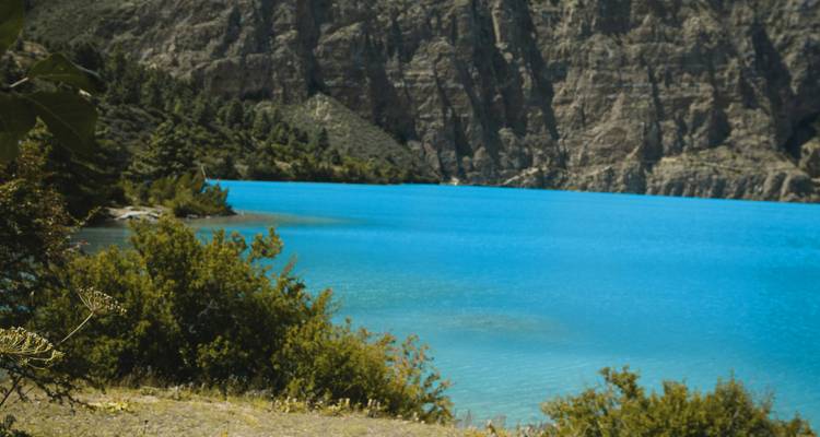 Lac bleu avec falaises et végétation environnantes.