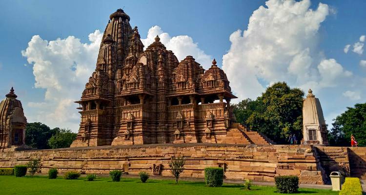 Ingewikkeld uitgehakte zandstenen tempel van Khajuraho tegen een helderblauwe lucht.