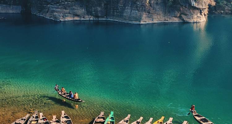 Helder blauw water met boten die drijven en rotsachtige kliffen in de buurt.